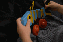 Wooden, multi-coloured painted fish on four wheels consisting of five moveable parts connected together