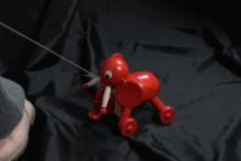 Wooden, multi-coloured painted fish on four wheels consisting of five moveable parts connected together